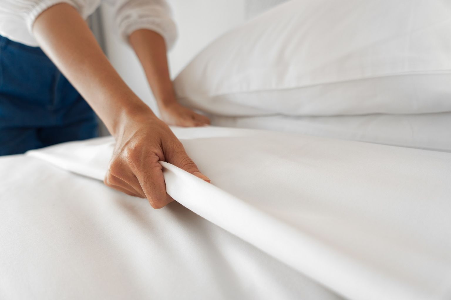 Uma pessoa cobre uma cama. Só se pode ver os braços e parte da cama.